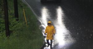 Christian "Chris" Lachance, 76, is undeterred by the rain as he makes his daily walk picking up trash on Hazel Mill Road in West Asheville.