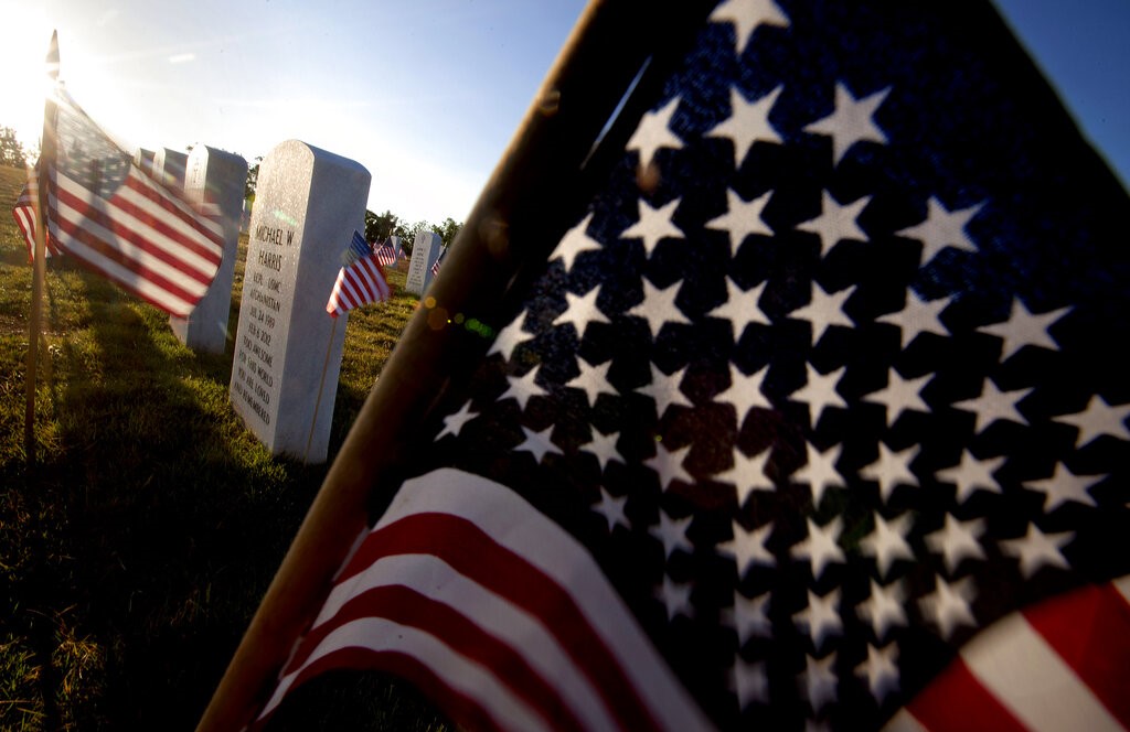 American flags wave near Marine Lance Cpl. Michael Harris' grave marker, center, as the the sun rises over Georgia National Cemetery Monday, May 28, 2012, in Canton, Ga. Harris died Feb. 6, 2012, in North Carolina. (AP Photo/David Goldman)