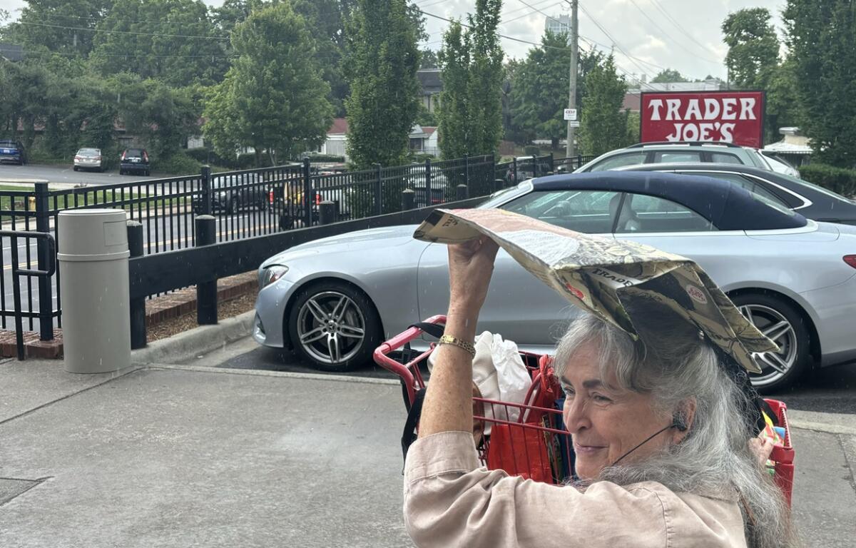 Suzie Hill, of Leicester, keeps out of the rain grocery shopping with a reusable bag.