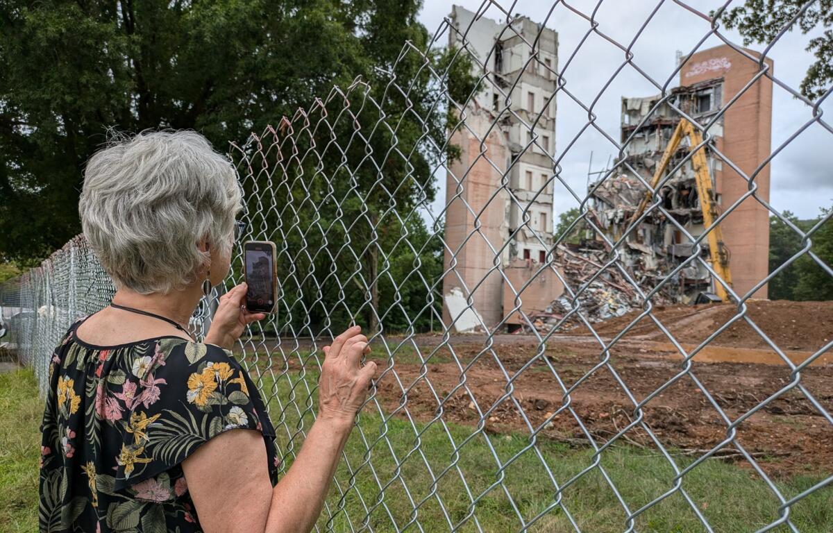 Lisa Schwartz of Candler takes a cell phone video as a large section of the former Haynes Tower came tumbling down on Thursday, July 25, 2024, at A-B Tech's campus in Enka.