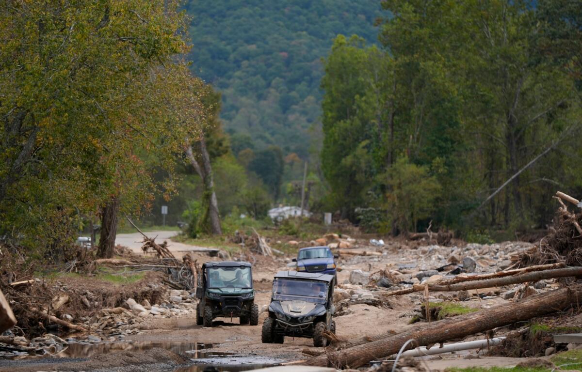 Vehicles roll along on a washed up road in the aftermath of Hurricane Helene, Thursday, Oct. 3, 2024, in Pensacola, N.C. (AP Photo/Mike Stewart)