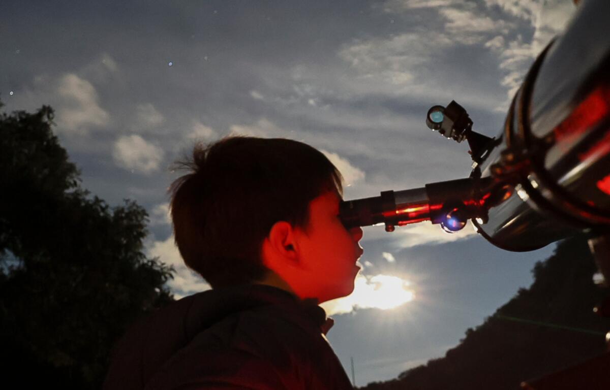 FILE - A youth looks through a telescope during a stargazing and comet-watching gathering at Joya-La Barreta Ecological Park in Queretaro, Mexico, Saturday, Oct. 19, 2024. (AP Photo/Ginnette Riquelme, File)
