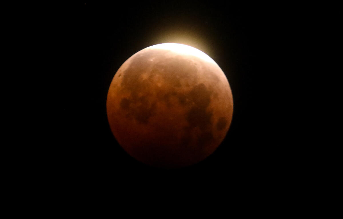 FILE - Light shines from a total lunar eclipse over Santa Monica Beach in Santa Monica, Calif., Wednesday, May 26, 2021. (AP Photo/Ringo H.W. Chiu, File)
