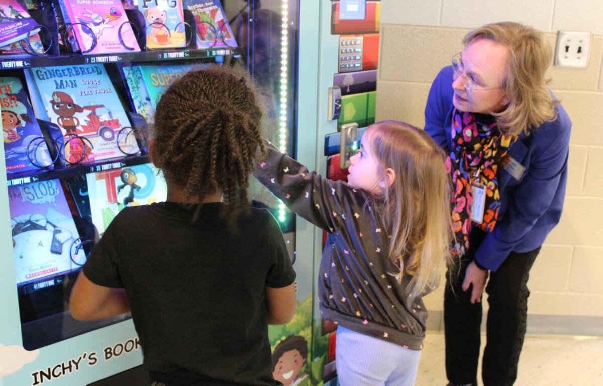 Sand Hill-Venable Elementary School principal Angela Gwyn watches while students Nation and Grace choose a book from the Inchy the Bookworm vending machine.