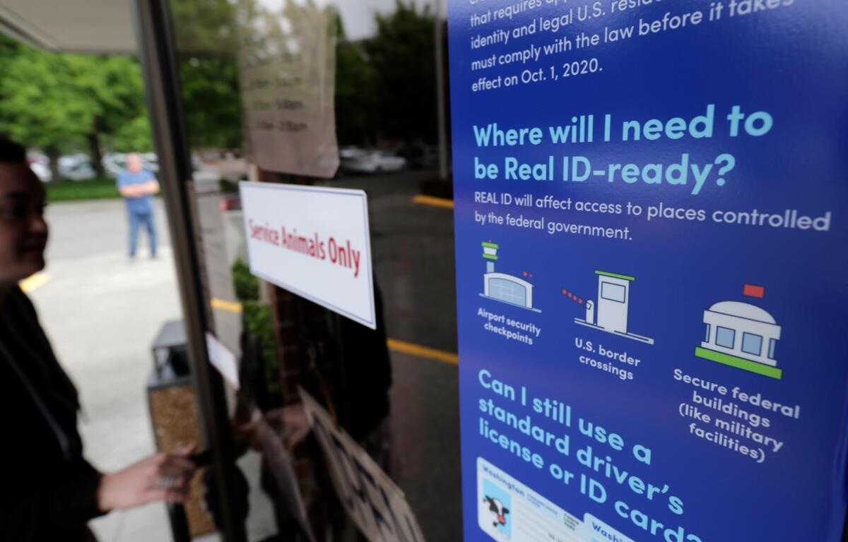 A customer opens the door of a Washington state Dept. of Licensing office in Lacey, Wash., Friday, June 22, 2018 next to a sign providing information about the requirements of Real ID. Some Washington licenses and identification cards will soon be marked with the words "federal limits apply" as the state moves to comply with a federal law that increased rules for identification needed at airports and federal facilities. (AP Photo/Ted S. Warren)