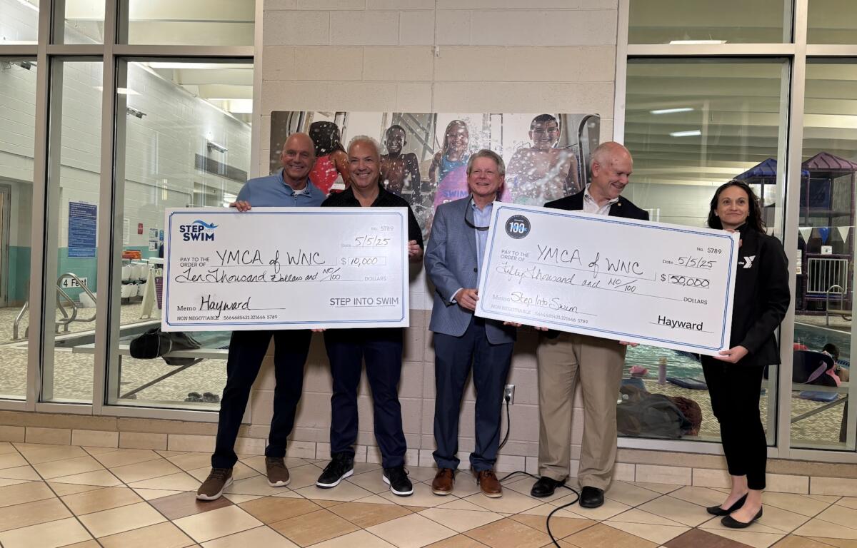 A crowd stands with two oversized checks.