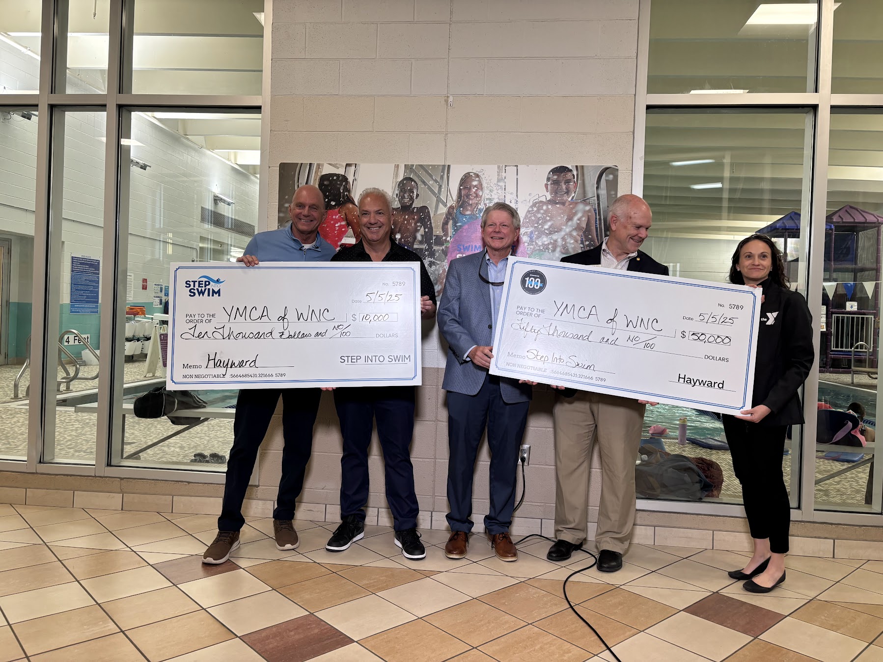 A crowd stands with two oversized checks.