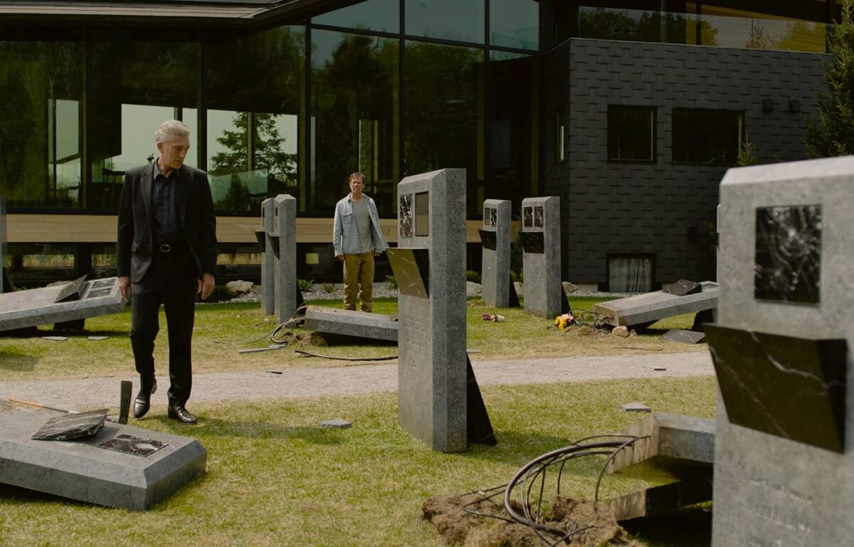 A man stands in a cemetery looking at vandalized digital gravestones.