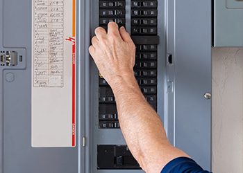An image of a man's hand flipping a switch in an electric breaker.