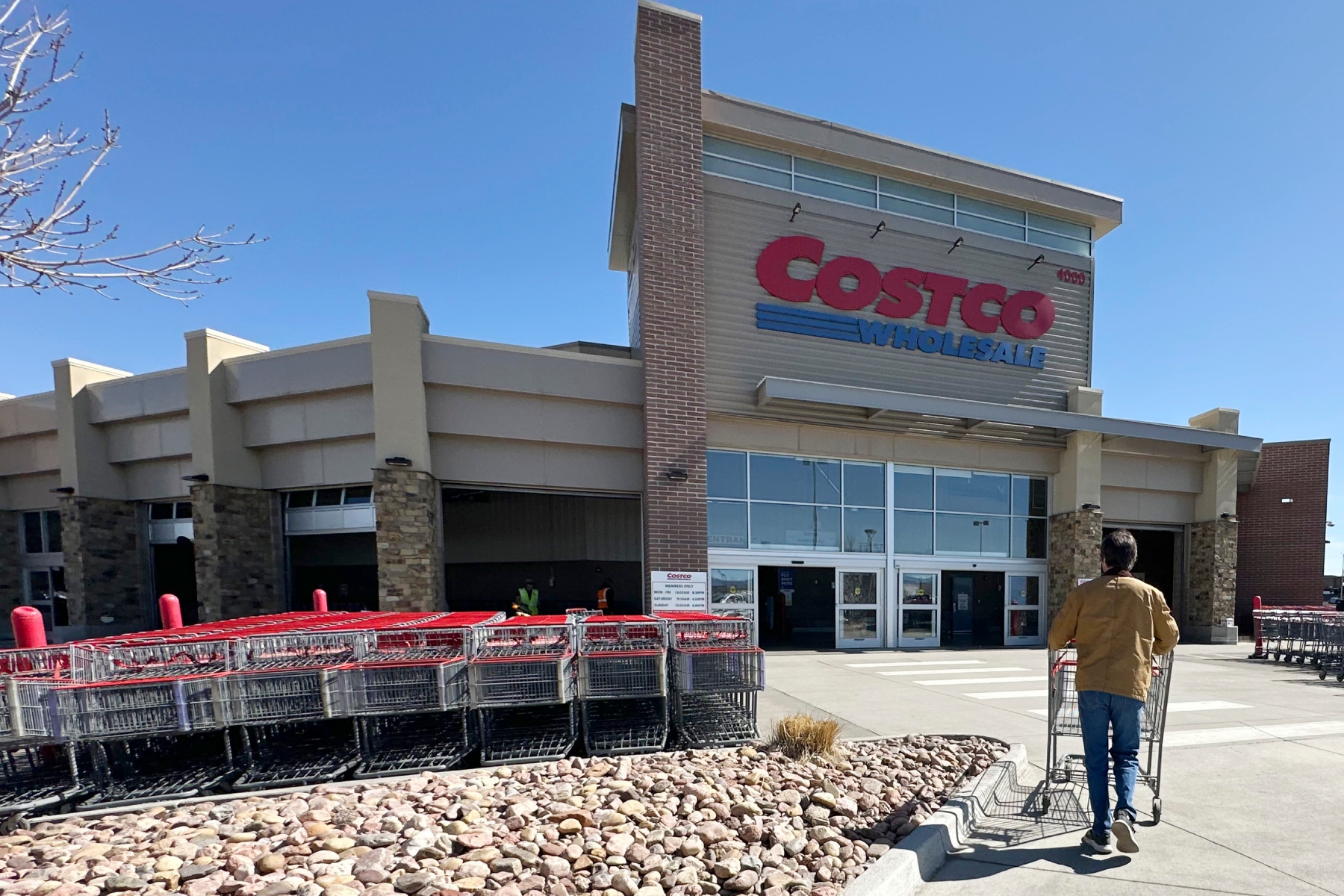 FILE - A lone shopper pushes a cart toward the entrance of a Costco warehouse, March 13, 2025, in Sheridan, Colo. (AP Photo/David Zalubowski, File)