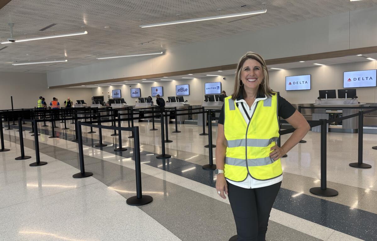 A woman in a safety vest stands in front of ticket counters.