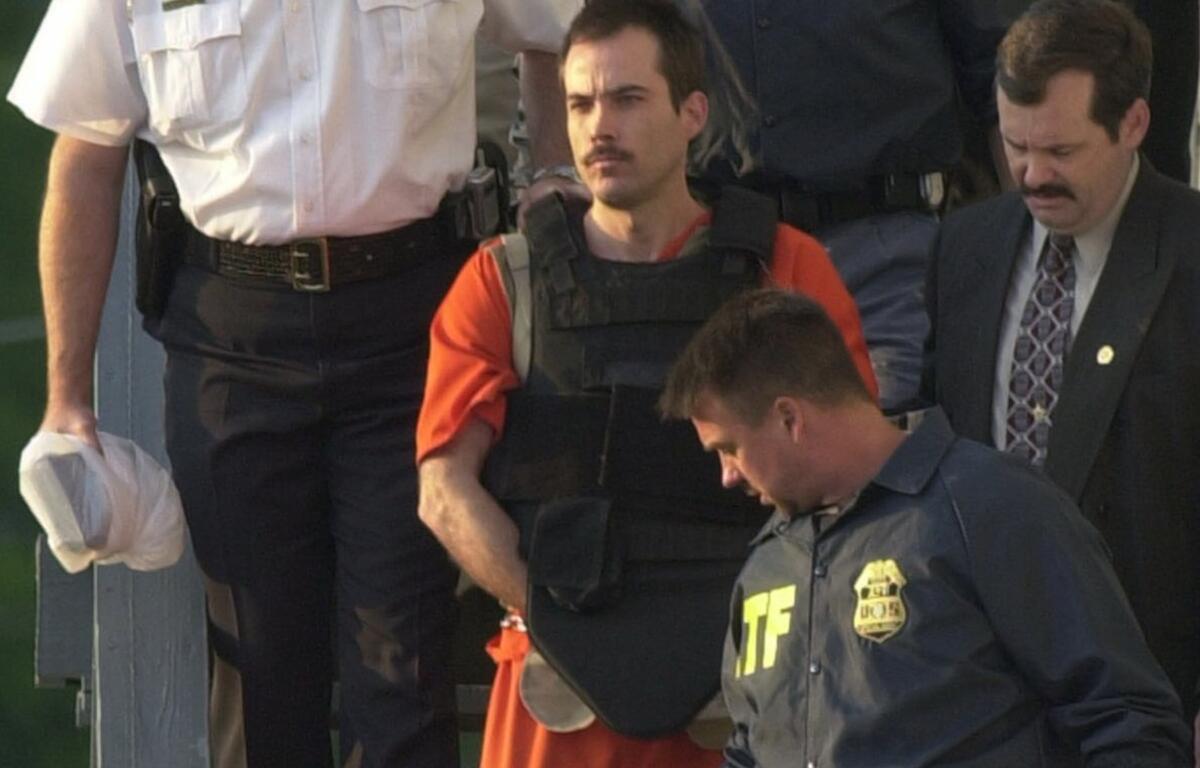 FILE - In this June 2, 2003 file photo, Eric Robert Rudolph, center, is escorted from the sheriff's department in Murphy, N.C. Rudolph has published his autobiography from prison with the help of his brother. Eric Rudolph pleaded guilty to setting off a bomb during the 1996 Olympics in Atlanta, and he also admitted to bombing a Birmingham abortion clinic in 1998. Two people died in the blasts. A prosecutor says authorities will look into seizing any money Rudolph might make from the book. The work explains his motive for the bombings and recounts his capture after more than five years on the run (AP Photo/Mary Ann Chastain)
