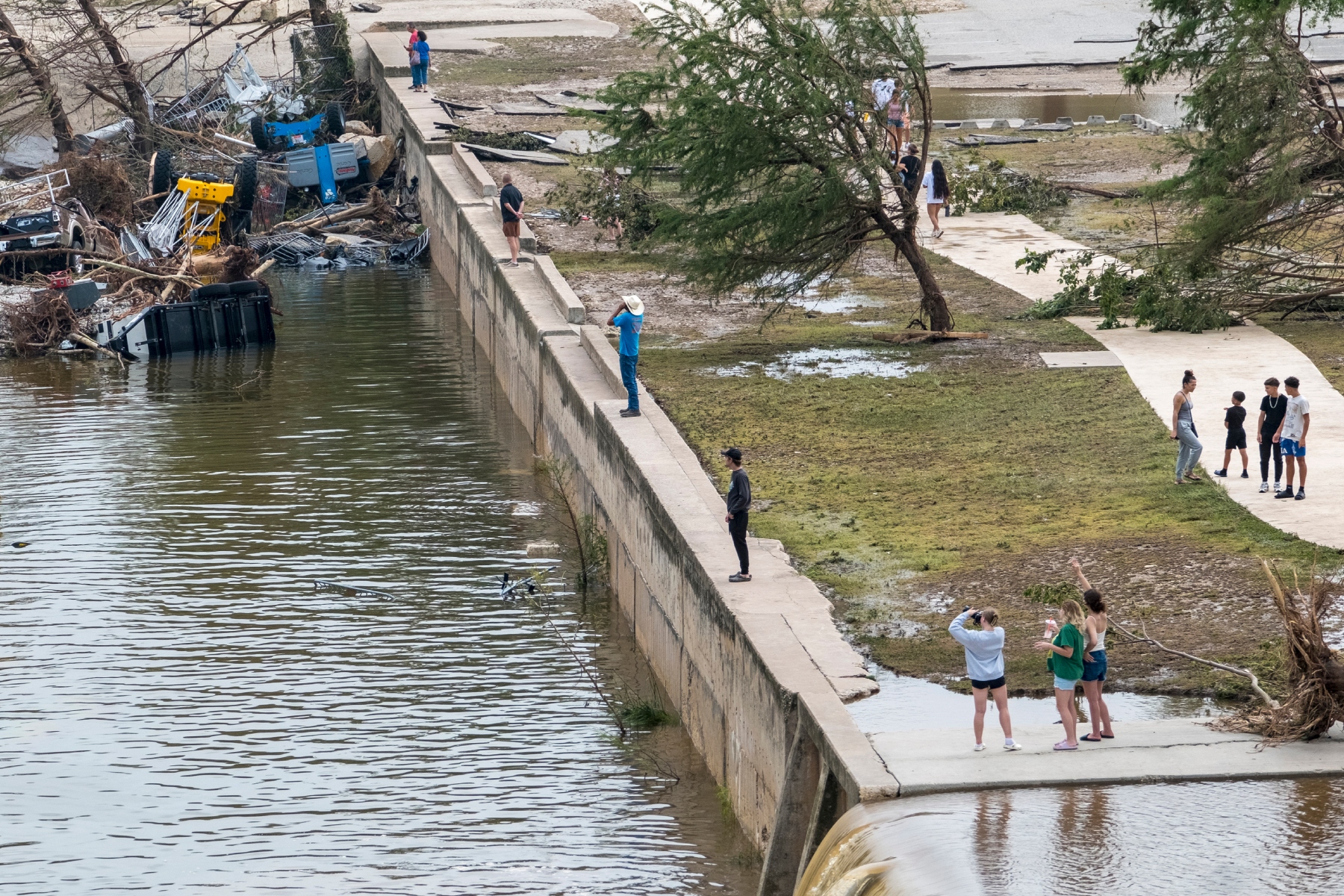 Onlookers walk along the banks of the Guadalupe River in Louise Hays Park, Saturday, July 5, 2025, in Kerrville, Texas. (AP Photo/Rodolfo Gonzalez)