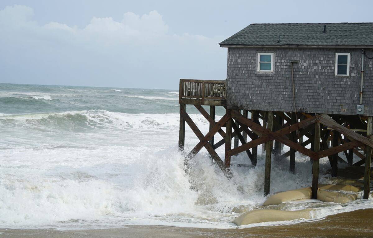 Waves from Hurricane Erin crash against the sandbagged pilings of a building in Buxton, N.C., on Wednesday, Aug. 20, 2025. (AP Photo/Allen G. Breed)