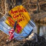 An American flag stands next to a sign written on housing debris along the Swannanoa River, Wednesday, Feb. 5, 2025, in Swannanoa, N.C. Swannanoa was one of several communities in western North Carolina that was severely affected by Hurricane Helene. (AP Photo/Kathy Kmonicek)