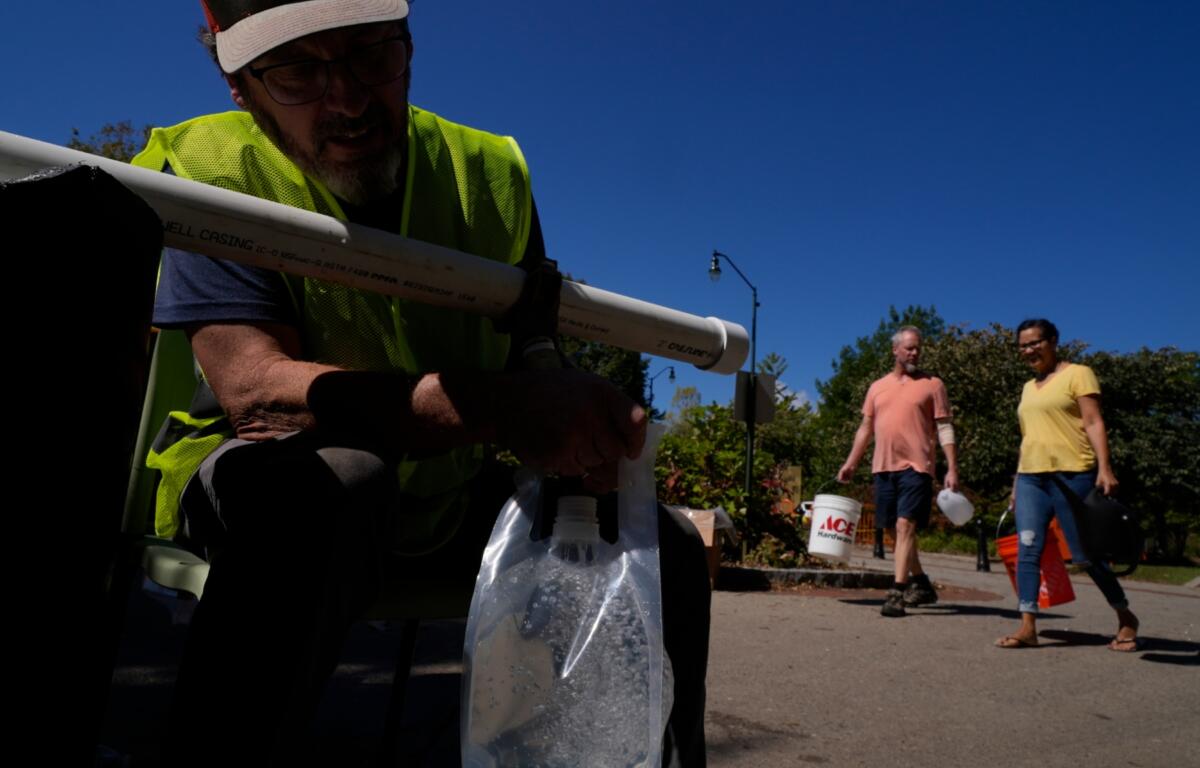 Michael Traister fills a bag of drinking water Thursday, Oct. 3, 2024 in Asheville, North Carolina. (AP Photo/Brittany Peterson)