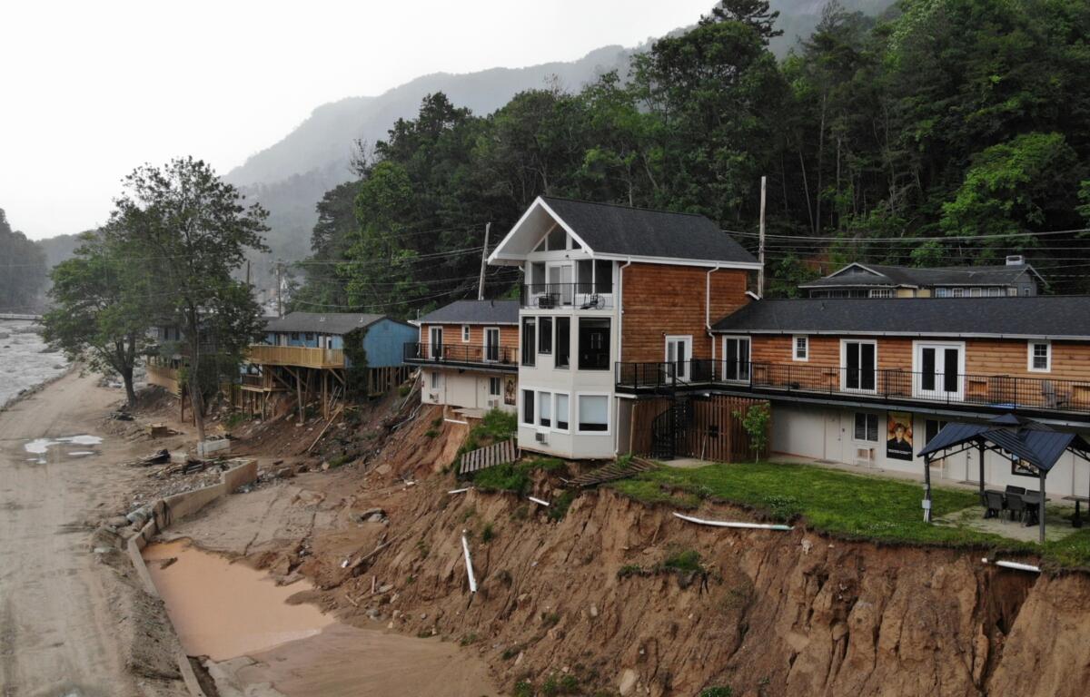 The Carter Lodge hangs precariously over the flood-scoured bank of the Broad River in Chimney Rock Village, N.C., on Tuesday, May 13, 2025. (AP Photo/Allen G. Breed)