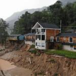 The Carter Lodge hangs precariously over the flood-scoured bank of the Broad River in Chimney Rock Village, N.C., on Tuesday, May 13, 2025. (AP Photo/Allen G. Breed)
