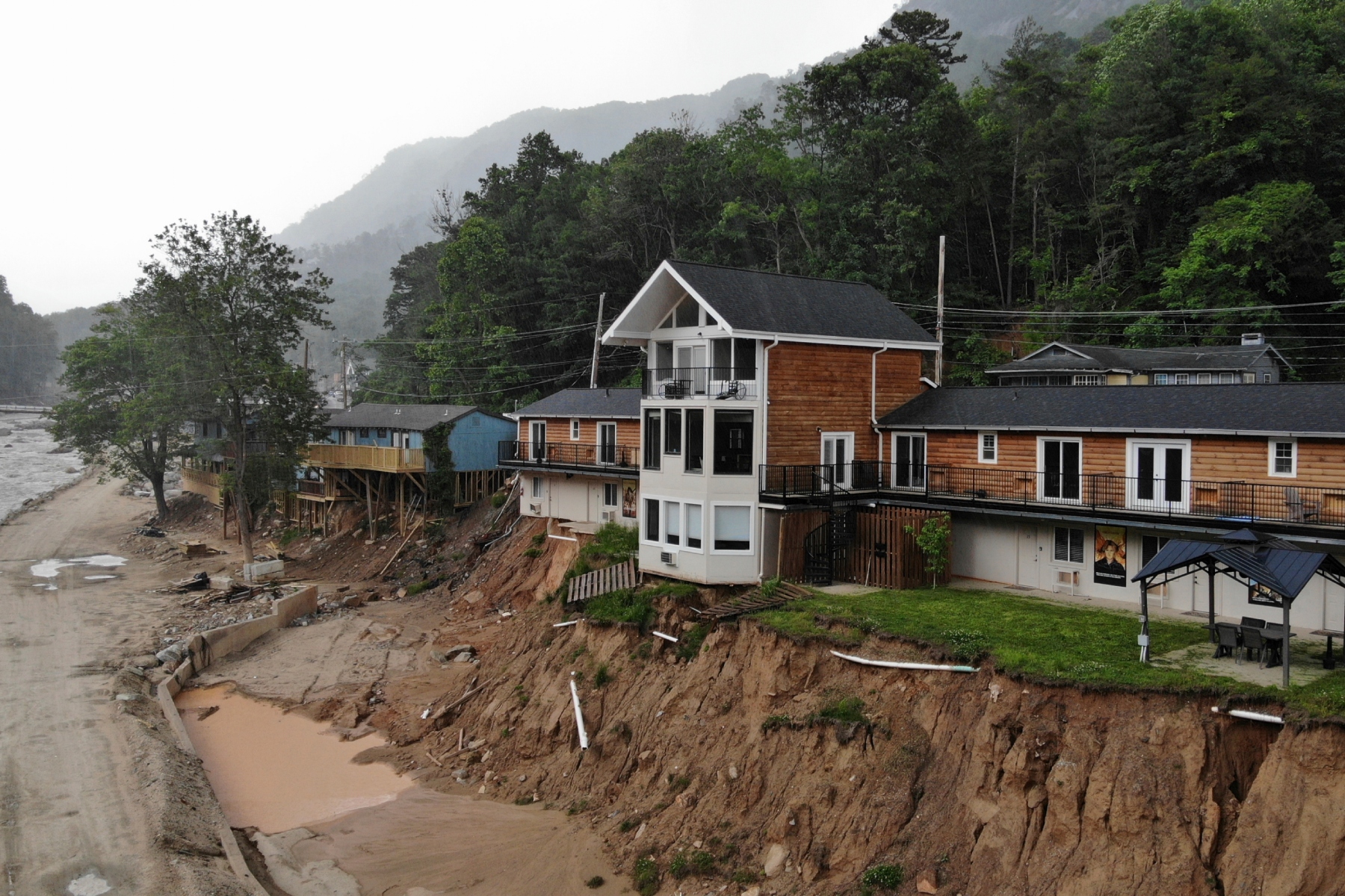 The Carter Lodge hangs precariously over the flood-scoured bank of the Broad River in Chimney Rock Village, N.C., on Tuesday, May 13, 2025. (AP Photo/Allen G. Breed)