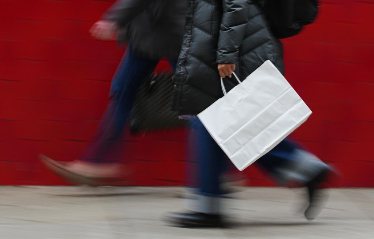 FILE - A person carries a shopping bag in Philadelphia, Dec. 10, 2025. (AP Photo/Matt Rourke, File)