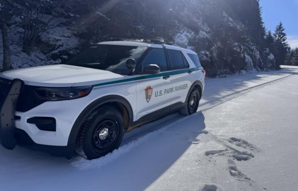 Law enforcement vehicle near a snow-covered mountainside.