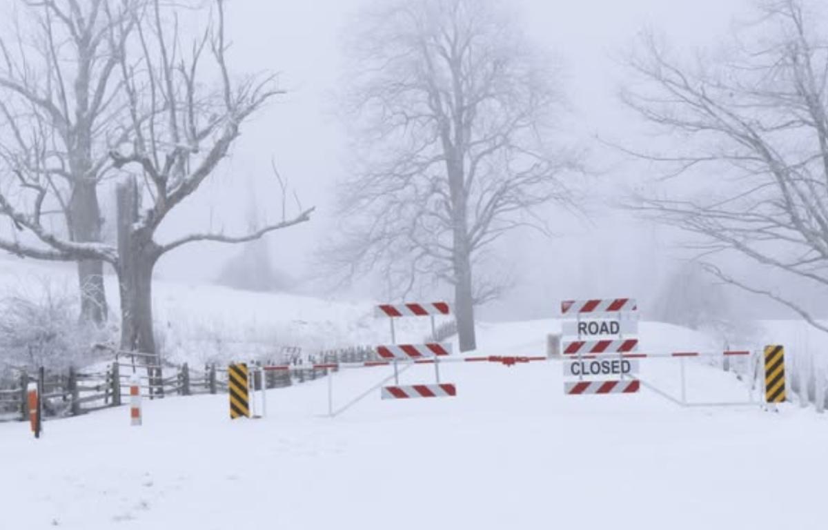 Parkway closure gate with snow-covered roadway and surrounding trees at Rocky Knob.