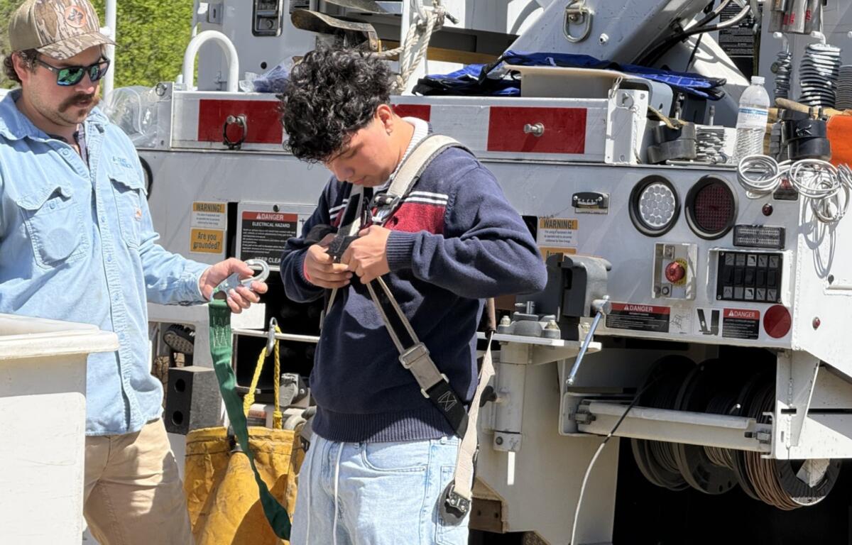 Sixteen-year-old Elmer Acevedo unbuckles after riding in the bucket of a utility truck.