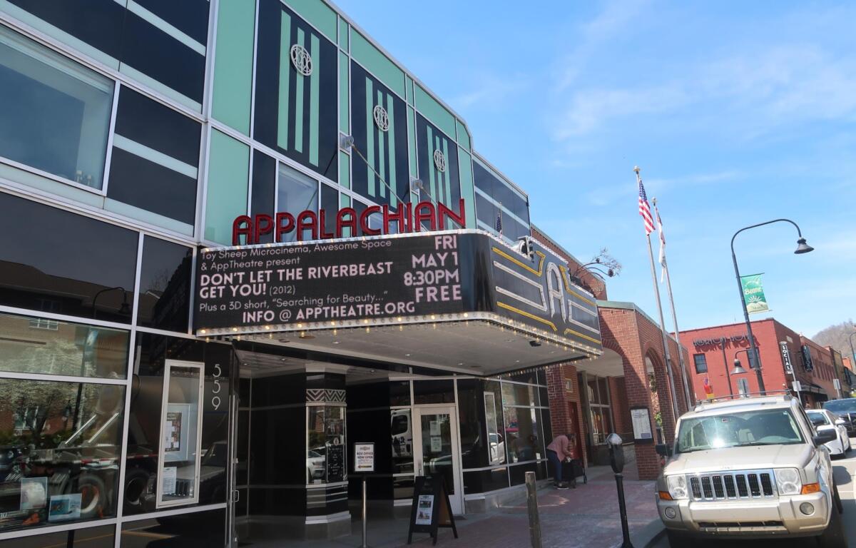 Facade of the Appalachian Theatre with a red APPALACHIAN sign and a marquee promoting a show on a sunny street.