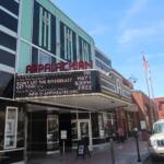 Facade of the Appalachian Theatre with a red APPALACHIAN sign and a marquee promoting a show on a sunny street.