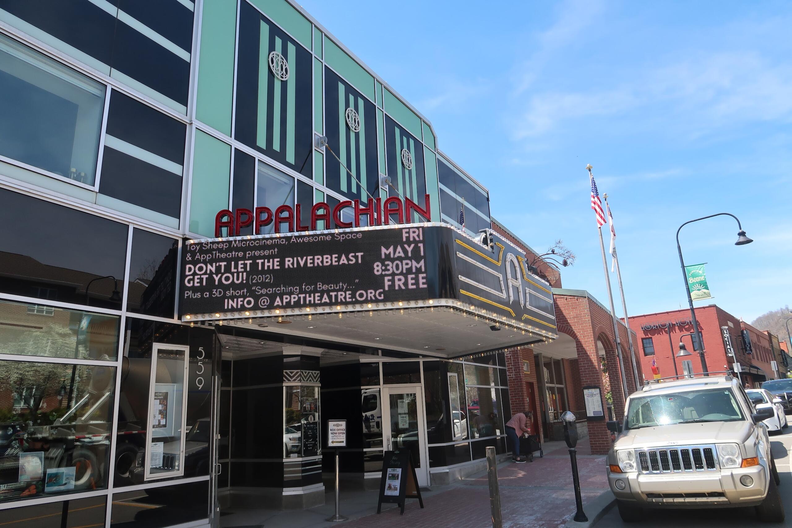 Facade of the Appalachian Theatre with a red APPALACHIAN sign and a marquee promoting a show on a sunny street.