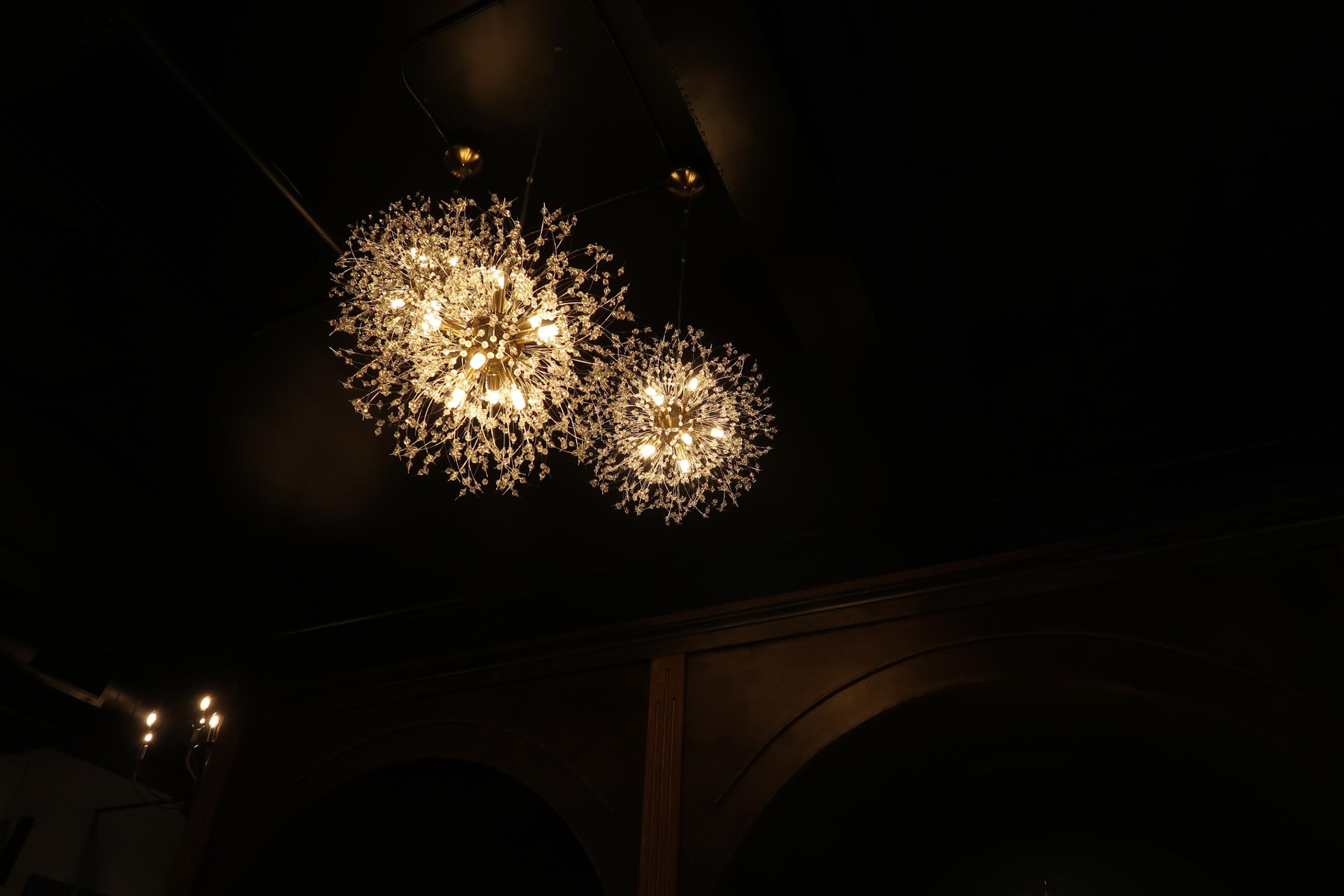 Two spherical crystal chandeliers glow warmly against a dark ceiling.