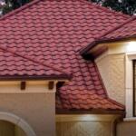 Red-tiled roof of a beige brick house, with a white arched entryway and large window with grid panes.
