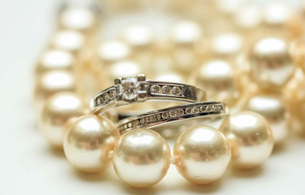 Close-up of pearl necklace with silver rings encrusted with small diamonds.