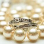 Close-up of pearl necklace with silver rings encrusted with small diamonds.