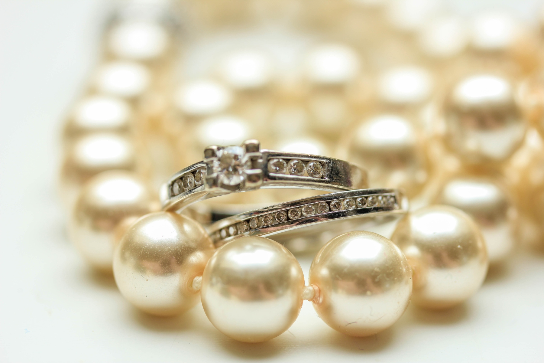 Close-up of pearl necklace with silver rings encrusted with small diamonds.