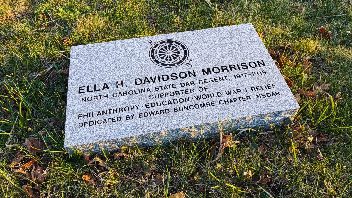 Granite grave marker on grass for Ella H. Davidson Morrison with a wheel design engraving at the top and inscription below.