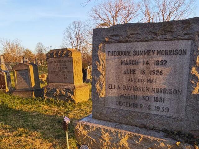 Granite grave marker in a sunny cemetery, reads Theodore Sum­mey Morrison (1852–1926) and Ella Davidson Morrison (1851–1939) with other worn headstones nearby.