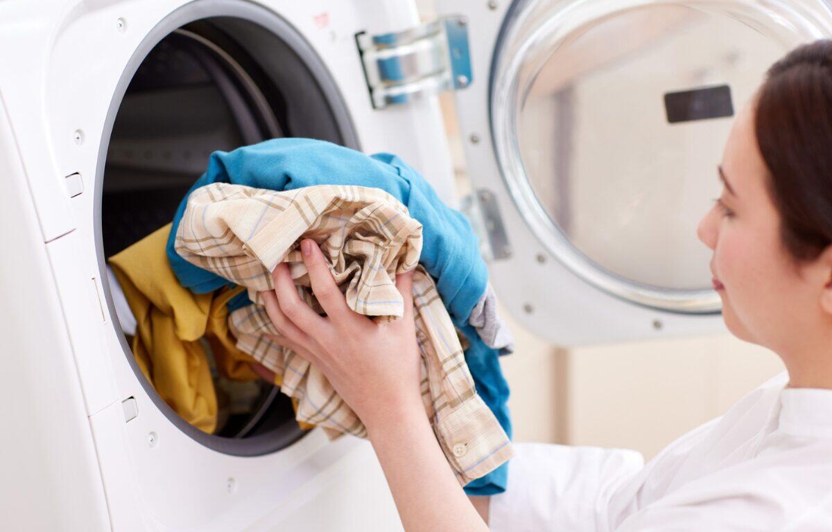 Image of woman places clothes in clothes dryer