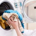 Image of woman places clothes in clothes dryer