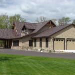 Beige two-story house with a three-car garage, brown shingle roof, and a neatly landscaped front yard.