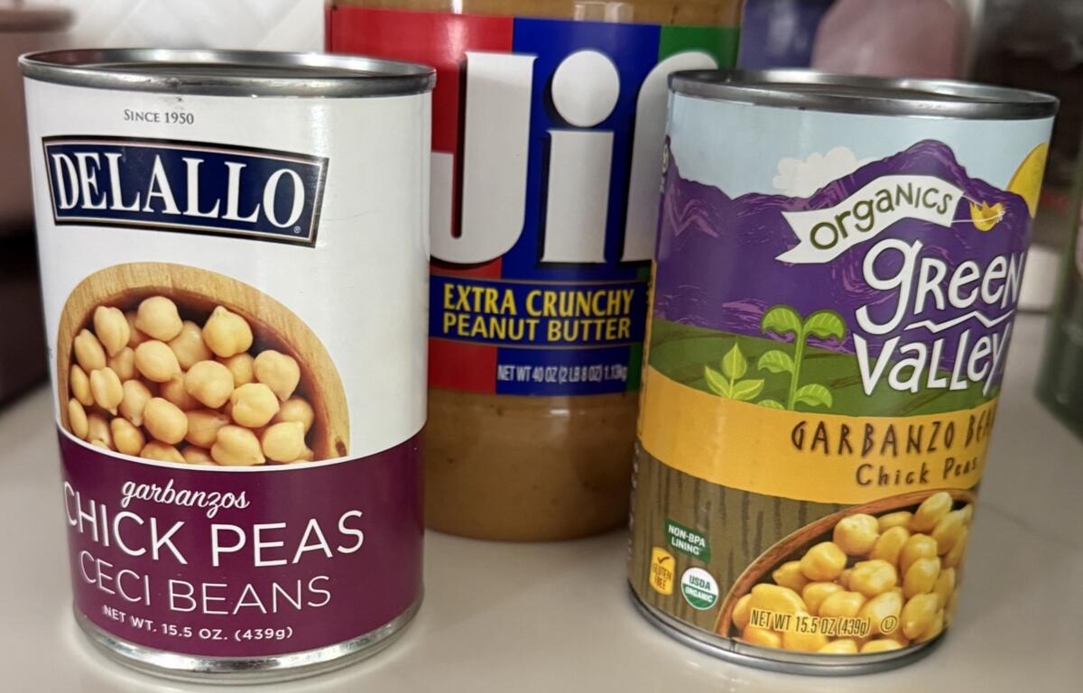 Three canned pantry items: Delallo chickpeas (garbanzo beans) on the left, Jif Extra Crunchy Peanut Butter in the center, and Green Valley Organics garbanzo beans on the right.