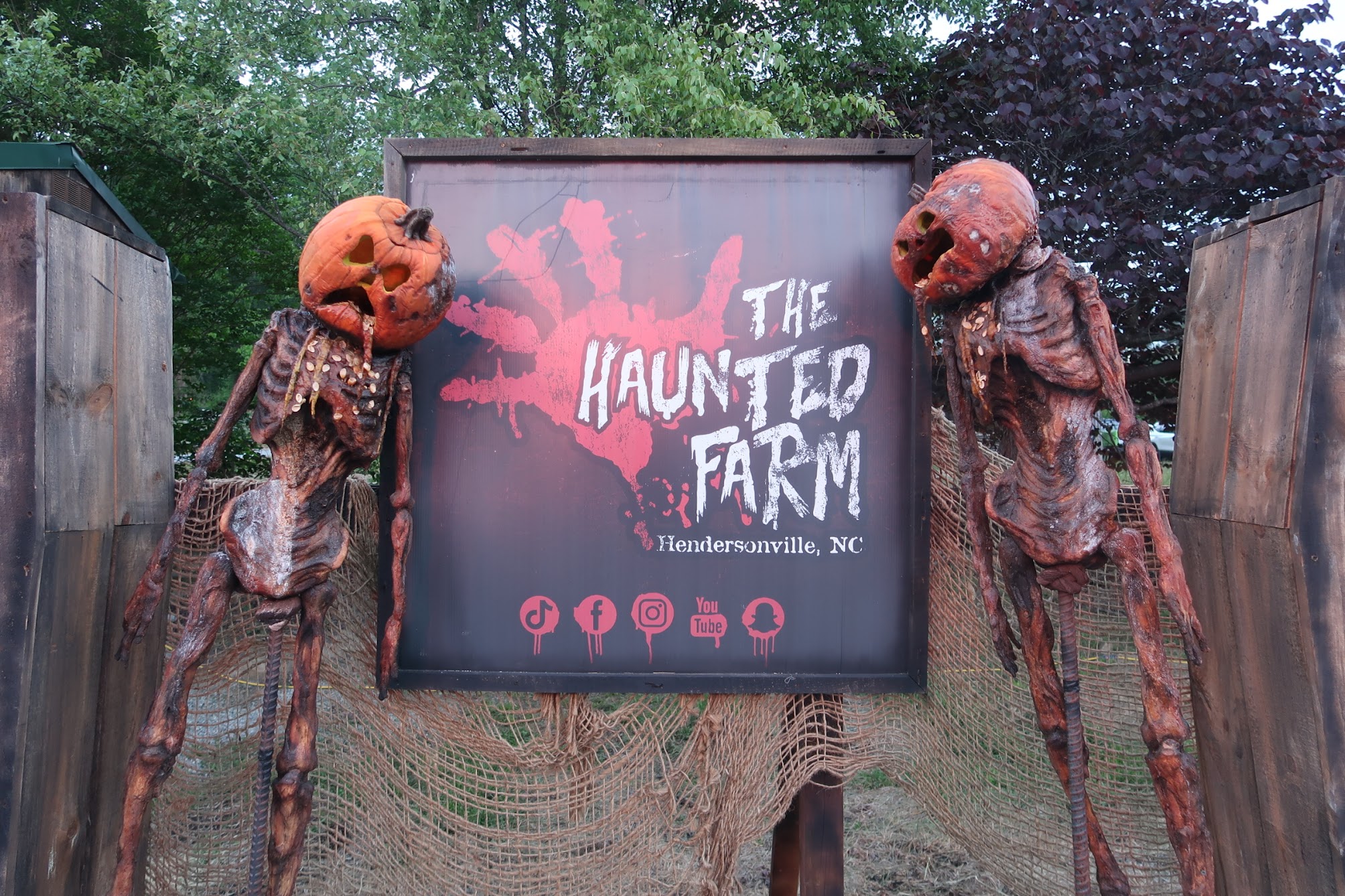 Haunted Farm entrance sign with two pumpkin-headed, skeletal figures on either side, Hendersonville, NC.