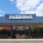 Smoky Mountain Cinema storefront with blue metal awning and promotional banners outside the entrance, under a blue sky.