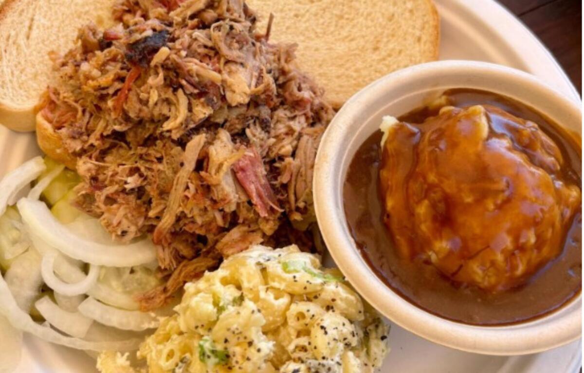 A chopped pork plate at Iron & Oak in Woodfin comes piled with moist barbecue, white bread, pickles and raw onion
