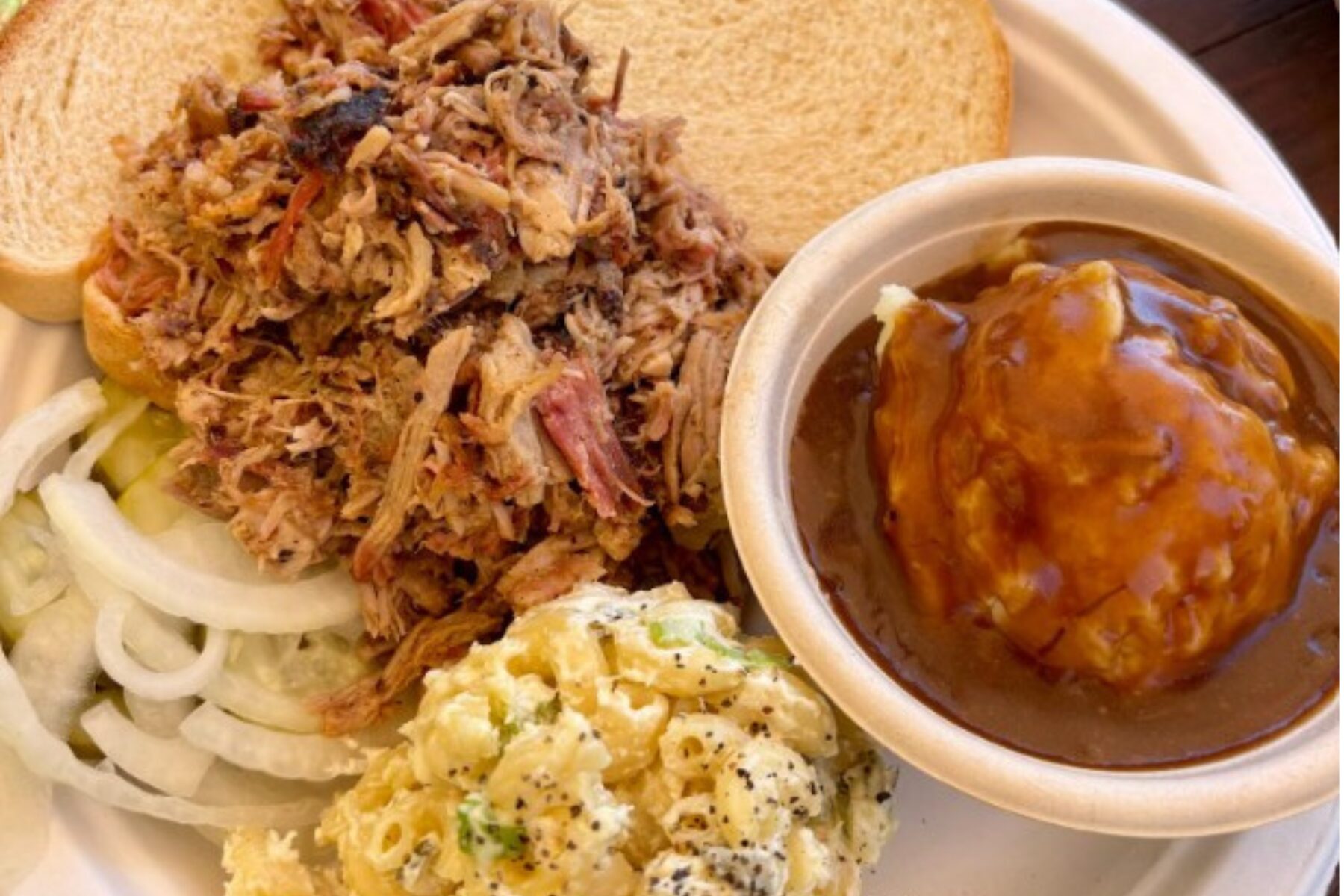 A chopped pork plate at Iron & Oak in Woodfin comes piled with moist barbecue, white bread, pickles and raw onion