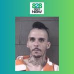 Mugshot of a man with a neck tattoo and mohawk in an orange jail uniform against a gray brick wall; 828 News Now logo above.