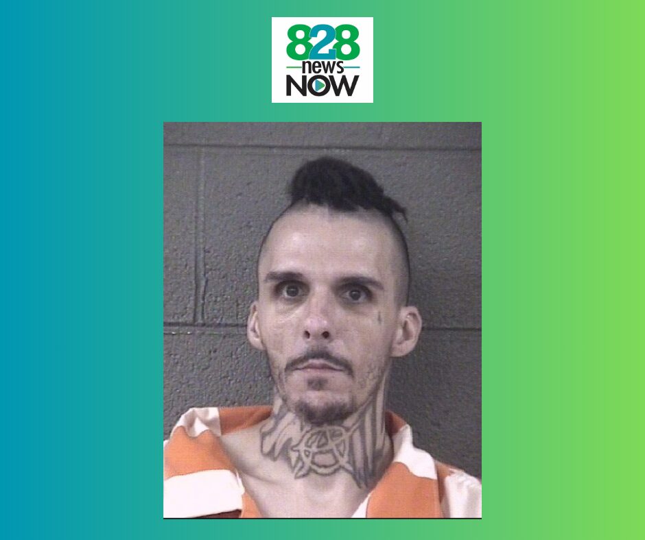Mugshot of a man with a neck tattoo and mohawk in an orange jail uniform against a gray brick wall; 828 News Now logo above.
