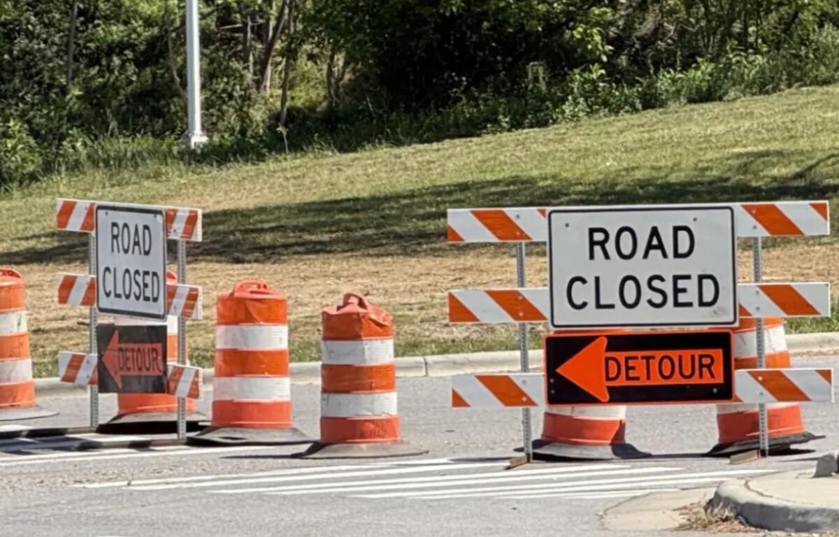 Road closed signs and orange traffic barriers blocking the street ahead