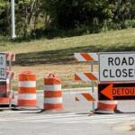 Road closed signs and orange traffic barriers blocking the street ahead