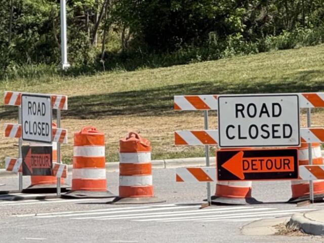 Road closed signs and orange traffic barriers blocking the street ahead